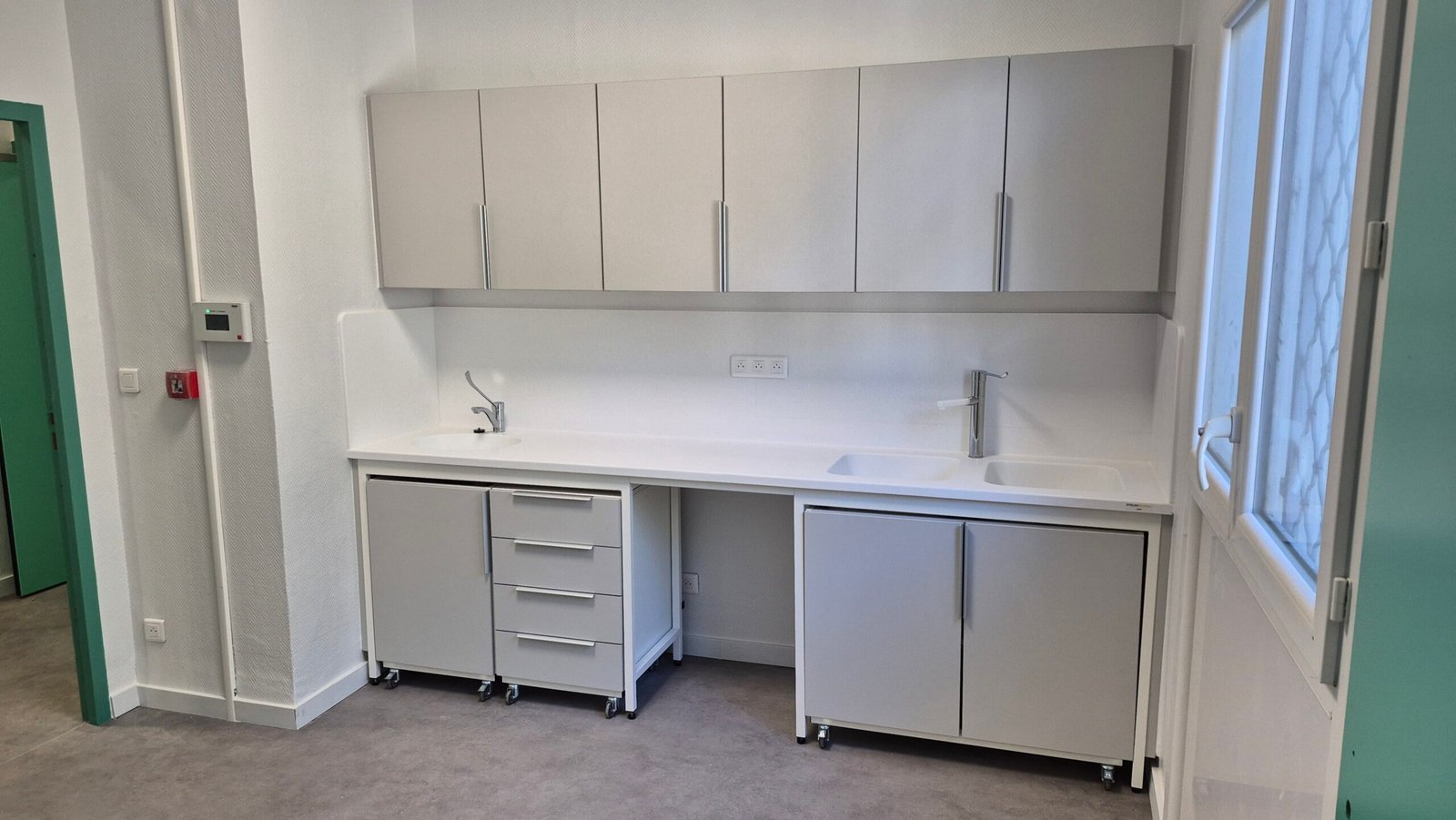 Paillasse de salle de soins avec deux points d’eau, rangements hauts et mobilier mobile